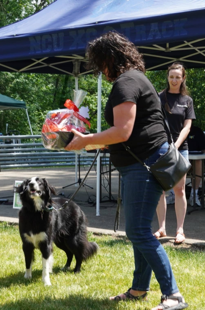A photo presenting a dog owner with a raffle basket at the Barks and Recreation event in 2023