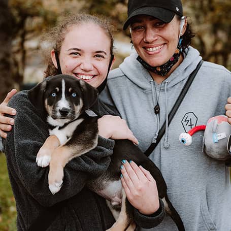 A photo of two people with one holding a puppy
